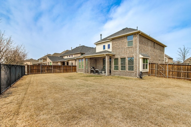 back of house with a patio area, brick siding, a yard, and a fenced backyard