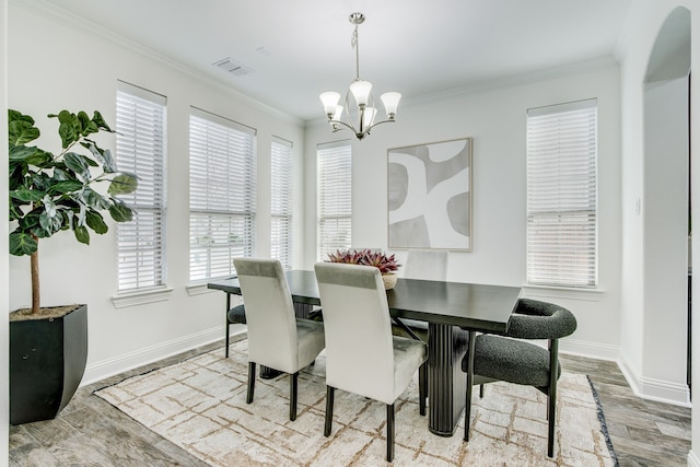 dining area with crown molding, visible vents, wood finished floors, a chandelier, and baseboards