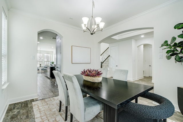 dining space featuring arched walkways, light wood-style floors, and an inviting chandelier