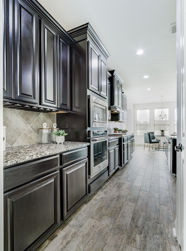 kitchen featuring tasteful backsplash, visible vents, appliances with stainless steel finishes, light stone counters, and recessed lighting