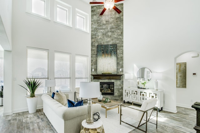 living area featuring baseboards, a fireplace, a high ceiling, and wood finished floors