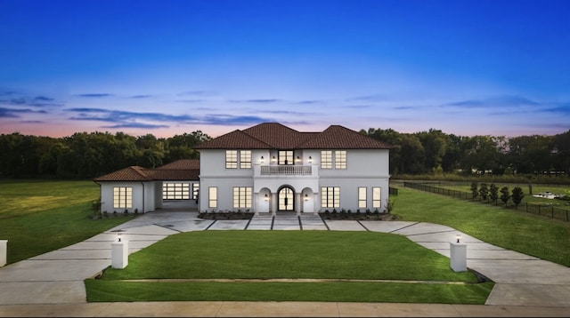 mediterranean / spanish-style house featuring a yard, stucco siding, a tile roof, and a balcony