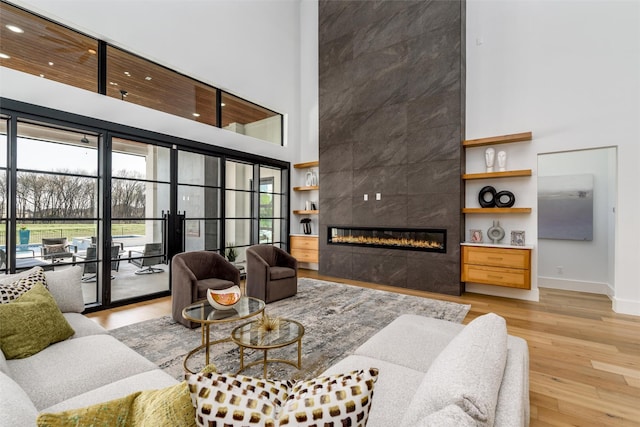 living room featuring wood finished floors, a fireplace, baseboards, and a towering ceiling