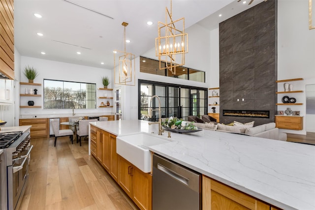 kitchen with open shelves, a high ceiling, a sink, light wood-style floors, and appliances with stainless steel finishes