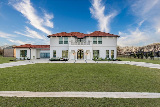 mediterranean / spanish home featuring a front lawn, stucco siding, french doors, a balcony, and driveway