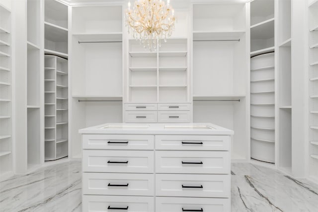 walk in closet featuring marble finish floor and a chandelier