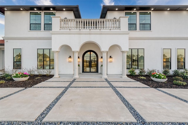 view of front of home featuring stucco siding, a balcony, and french doors