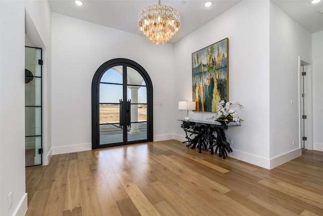 foyer entrance with wood finished floors, baseboards, recessed lighting, arched walkways, and french doors