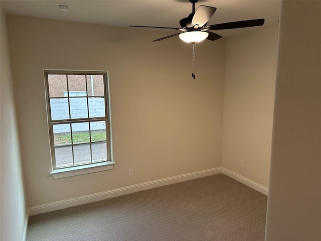 carpeted empty room with a ceiling fan and baseboards