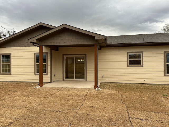 back of property featuring a shingled roof and a patio