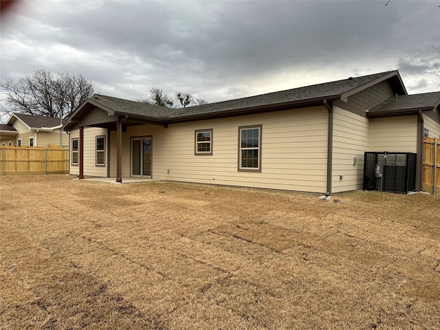 rear view of property featuring a shingled roof, fence, cooling unit, and a patio