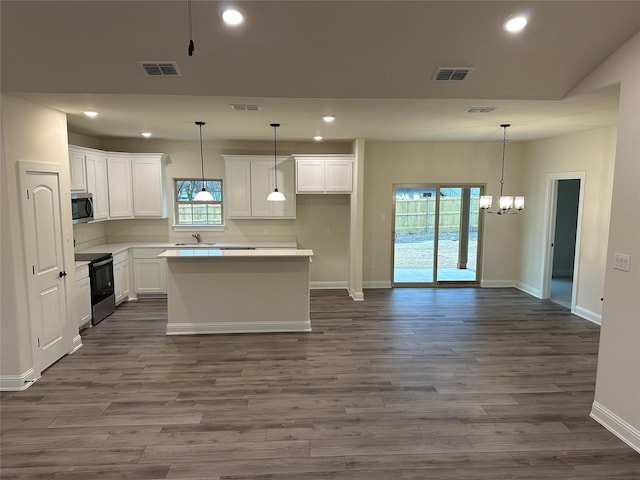 kitchen featuring electric range, stainless steel microwave, and visible vents