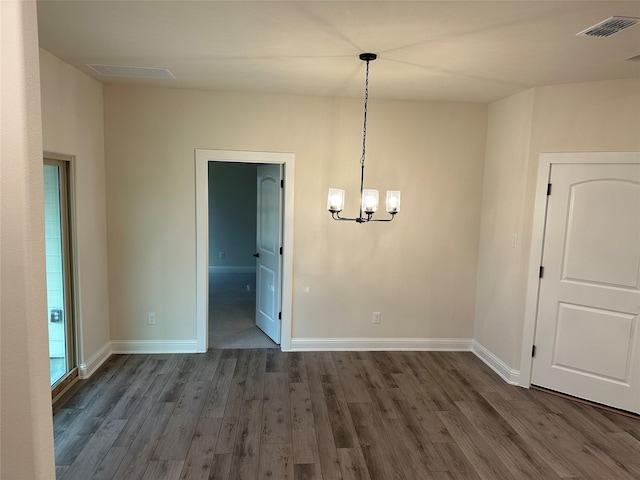 unfurnished dining area featuring baseboards, visible vents, a chandelier, and dark wood-style flooring