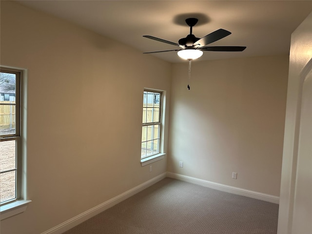 carpeted spare room with ceiling fan and baseboards