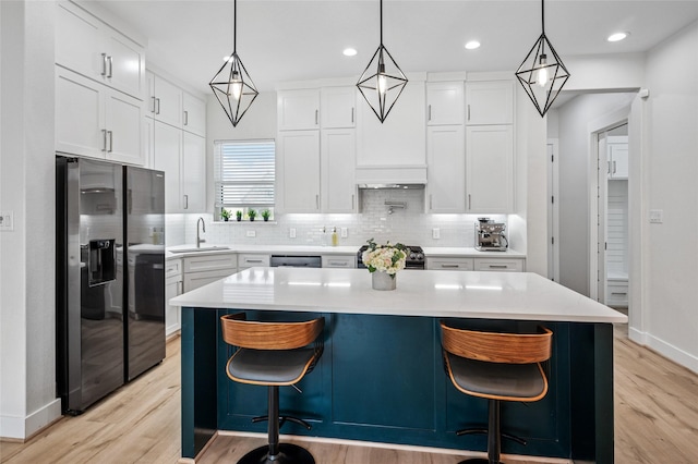 kitchen featuring stainless steel refrigerator with ice dispenser, backsplash, white cabinets, light countertops, and stove