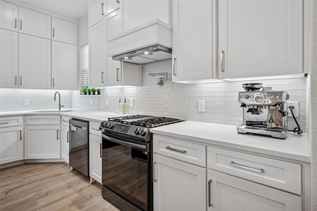 kitchen featuring premium range hood, a sink, stainless steel appliances, light countertops, and white cabinets