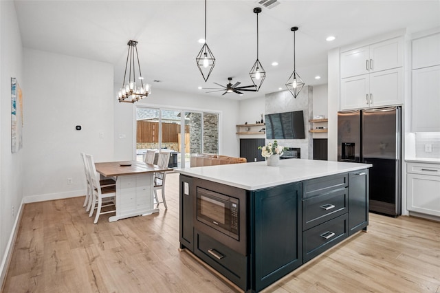 kitchen with built in microwave, a fireplace, white cabinetry, and stainless steel fridge with ice dispenser