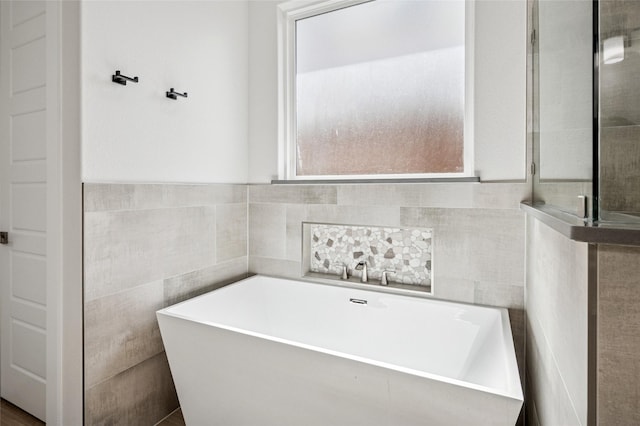 full bathroom with a soaking tub and tile walls