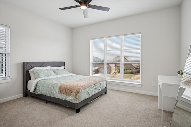 bedroom with a ceiling fan, baseboards, and light carpet