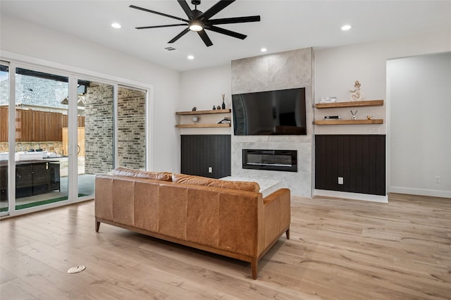 living area featuring a ceiling fan, visible vents, recessed lighting, light wood-style floors, and a large fireplace