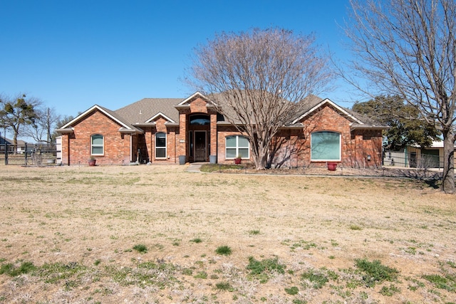 ranch-style house featuring brick siding, a front yard, and fence