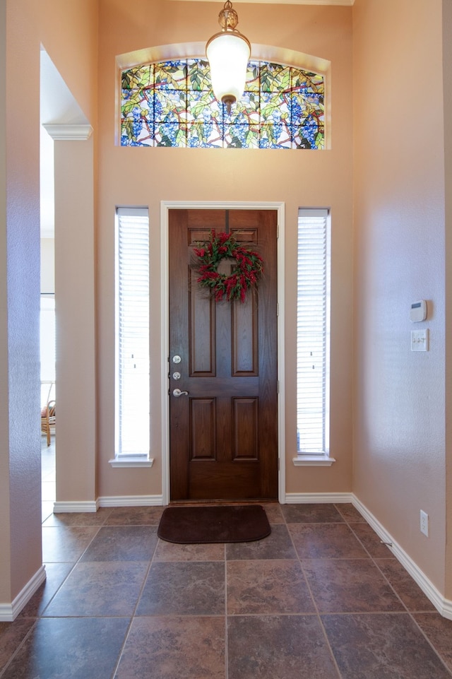 foyer with stone finish floor, a high ceiling, and baseboards