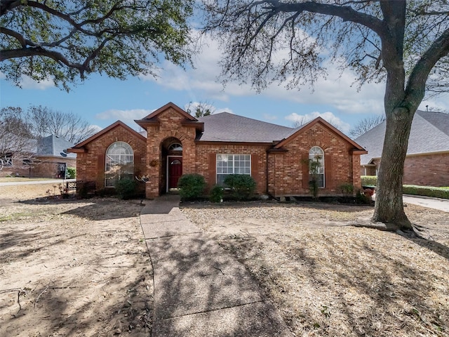 view of front of home with brick siding and roof with shingles