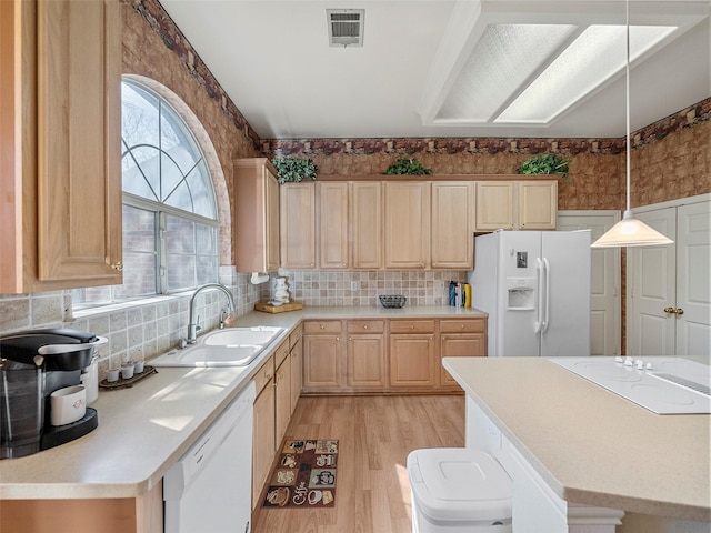 kitchen featuring visible vents, light brown cabinets, a sink, light wood-type flooring, and white appliances