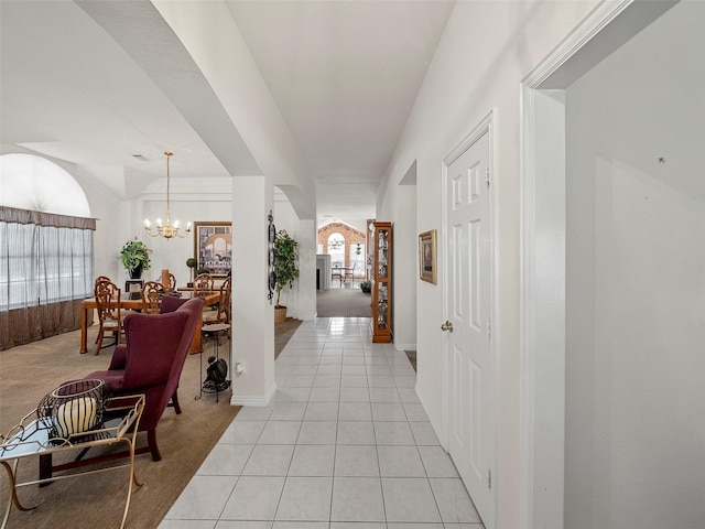 hallway with arched walkways, light tile patterned flooring, and a notable chandelier