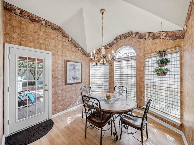 dining area featuring vaulted ceiling, a chandelier, light wood-style flooring, and baseboards