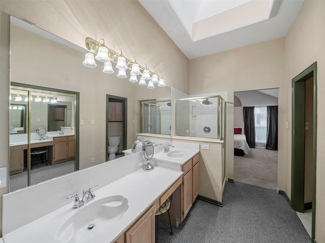 ensuite bathroom with a skylight, a stall shower, two vanities, and a sink