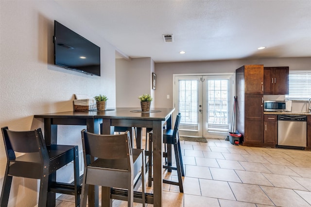 dining room with french doors, a healthy amount of sunlight, visible vents, and light tile patterned floors