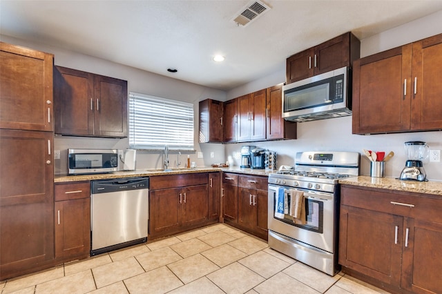 kitchen featuring light tile patterned floors, visible vents, light stone countertops, stainless steel appliances, and a sink