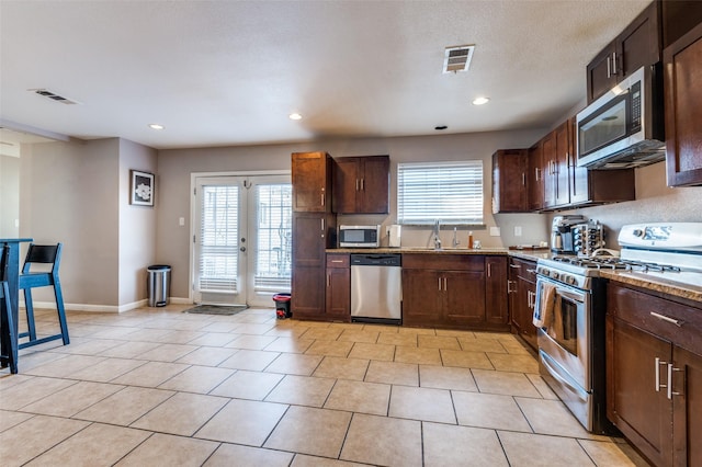 kitchen with a healthy amount of sunlight, light tile patterned floors, visible vents, and appliances with stainless steel finishes