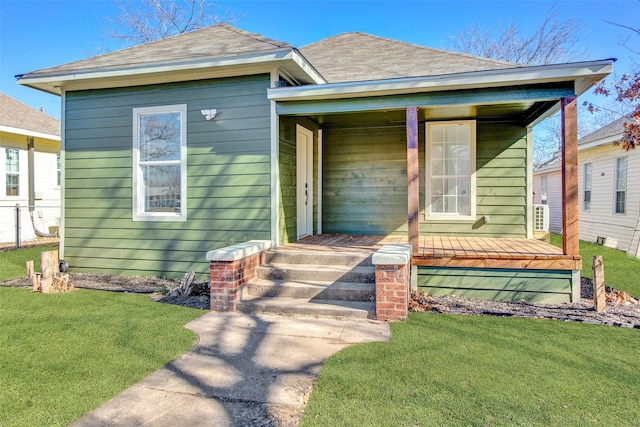 view of front of home featuring a shingled roof, a front yard, and covered porch