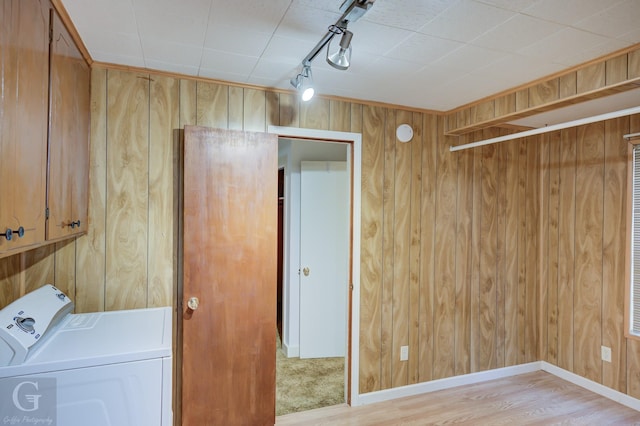 laundry area with cabinet space, light wood finished floors, wooden walls, baseboards, and rail lighting