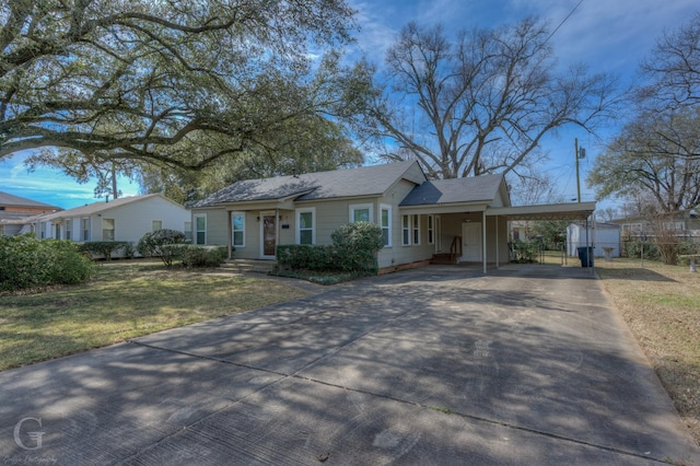 ranch-style house with driveway, fence, an attached carport, and a front yard