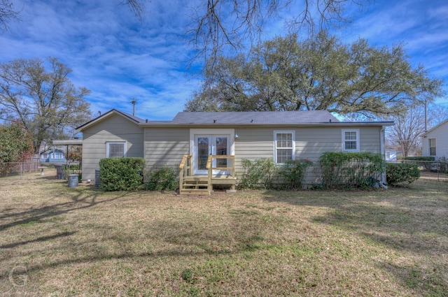 rear view of property featuring a yard, french doors, and fence