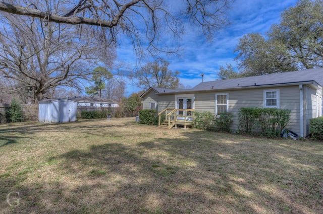 back of house featuring an outdoor structure, fence, a yard, french doors, and a storage unit