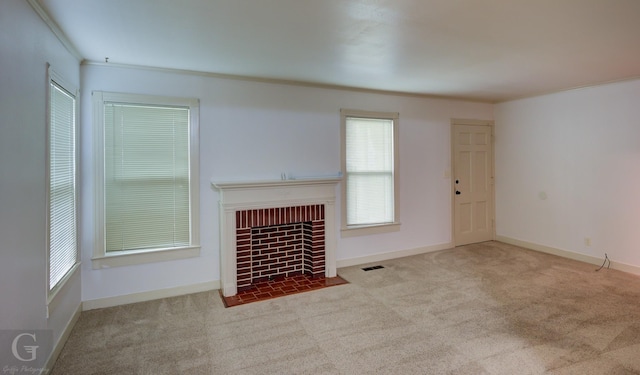 unfurnished living room featuring a fireplace with flush hearth, visible vents, baseboards, ornamental molding, and carpet