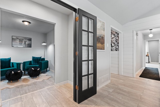 corridor with lofted ceiling, wood finished floors, visible vents, and baseboards