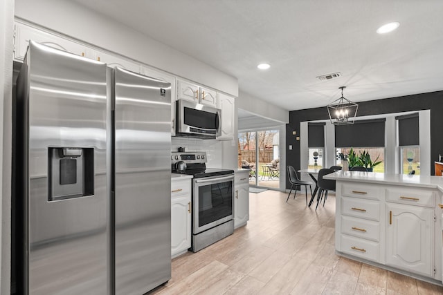 kitchen featuring visible vents, white cabinetry, light countertops, appliances with stainless steel finishes, and decorative light fixtures