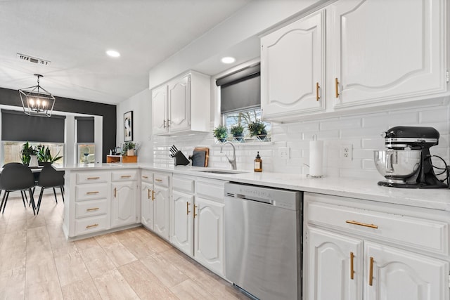 kitchen with a peninsula, a sink, visible vents, white cabinetry, and dishwasher