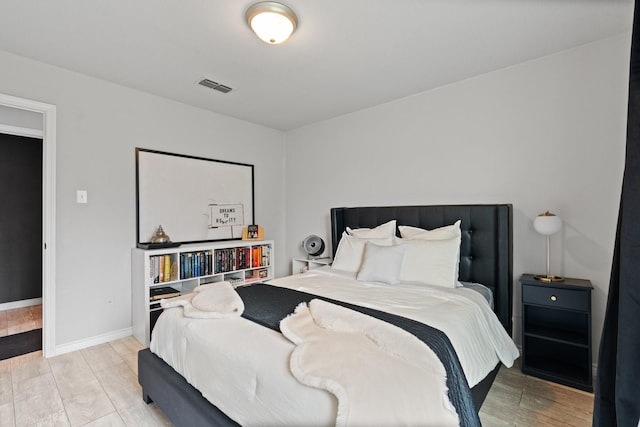 bedroom with visible vents, baseboards, and wood finished floors