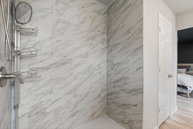 ensuite bathroom featuring a tile shower, wood finished floors, and ensuite bathroom