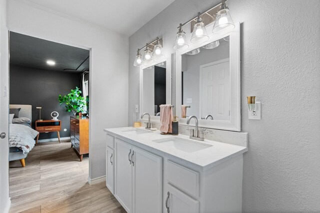 ensuite bathroom featuring wood finished floors, double vanity, a sink, and ensuite bathroom