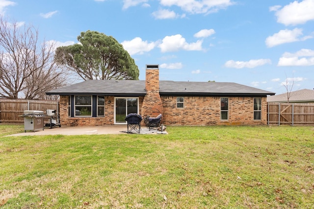 back of property with a fenced backyard, a chimney, a yard, a patio area, and brick siding