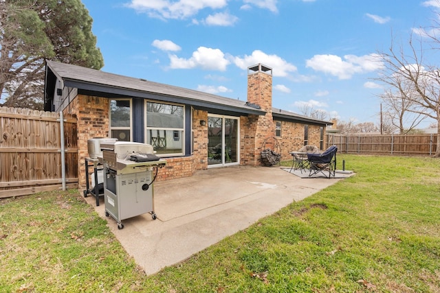 back of house with a patio, a fenced backyard, brick siding, a lawn, and a chimney