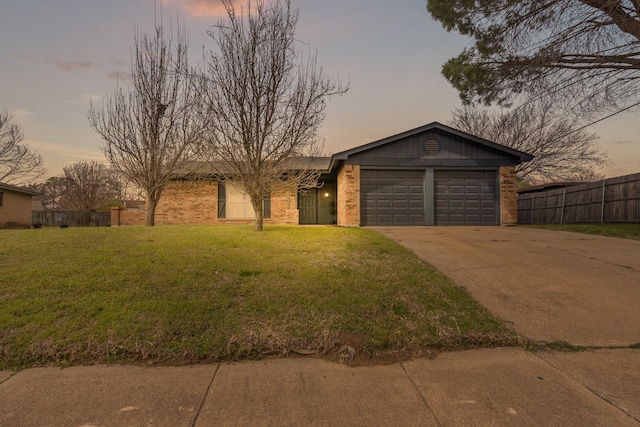 view of front of house with concrete driveway, an attached garage, fence, a front lawn, and brick siding