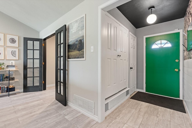 entrance foyer with vaulted ceiling, visible vents, wood finish floors, and french doors